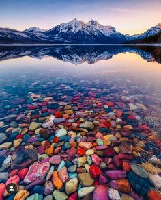 a lake that has some rocks in it and mountains in the backgroung