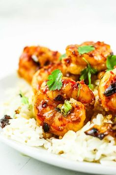 a white plate topped with rice covered in shrimp and garnished with cilantro