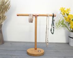 a wooden stand with several bracelets on it next to flowers and a potted plant