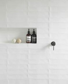 two bottles are sitting on a shelf in the bathroom, one is black and white