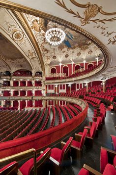 an empty auditorium with red seats and chandelier