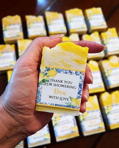 a hand holding a small bar of soap in front of rows of yellow and white bars