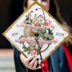 a woman holding up a decorated graduation cap