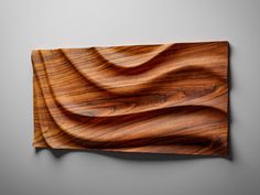 a wooden wall hanging on the side of a gray wall with wavy woodgrain