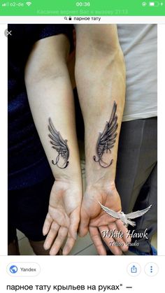 two people are holding hands with tattoos on their arms and the other hand has a feather in it