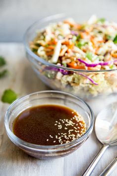 a salad with dressing in a bowl and spoons on the table next to it