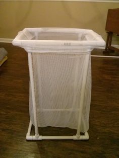 a white laundry hamper sitting on top of a wooden floor