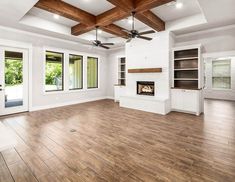 an empty living room with wood flooring and ceiling fans in the middle of it