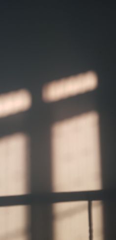 a cat sitting on top of a wooden table next to a window with light coming through it