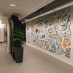 an office hallway with graffiti on the wall and potted plant next to it,