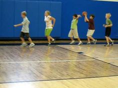 young people playing basketball on an indoor court with blue walls and hard wood flooring