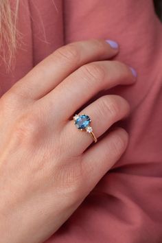 a woman's hand with a gold ring and blue topazte on it