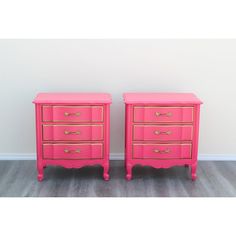 pair of pink and gold nightstands with brass handles on each side, in front of a white wall