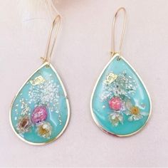 a pair of earrings with flowers painted on them