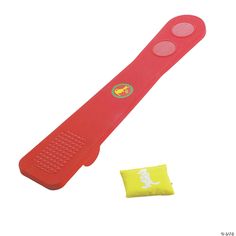 an orange and red plastic object next to a yellow piece of cloth on a white background