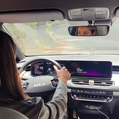 the woman is driving her car and taking a selfie