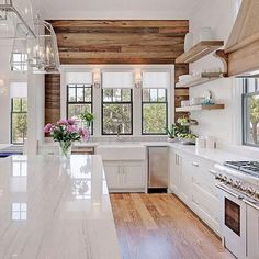 a large kitchen with white cabinets and wooden walls, along with an island in the middle