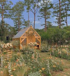 a small wooden building surrounded by flowers and trees