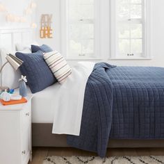 a bedroom with white walls and blue bedding