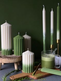 some candles are sitting on a table next to a glass of green liquid and other items