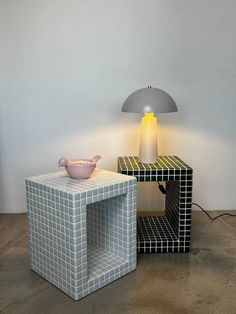 two different colored lamps sitting next to each other on a wooden floor in front of a white wall