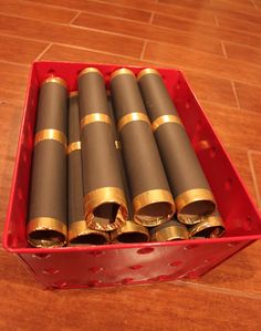 a red box filled with lots of gold and black tubes on top of a wooden floor