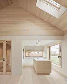 an empty kitchen with wooden floors and skylights above it is seen from the living room