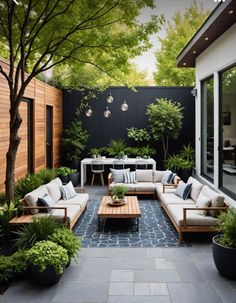 an outdoor living area with couches, tables and potted trees in the background