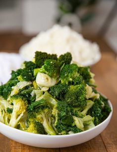 a white bowl filled with broccoli on top of a wooden table