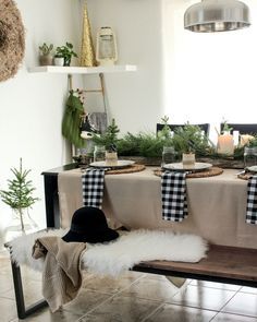 the table is set for christmas dinner with black and white plaid napkins on it