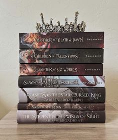 a stack of books sitting on top of a wooden table next to a tiara