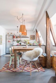 a dining room table and chairs in front of an open kitchen area with wooden beams