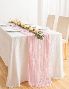 the table is set with white plates and pink runneres, along with flowers on each side