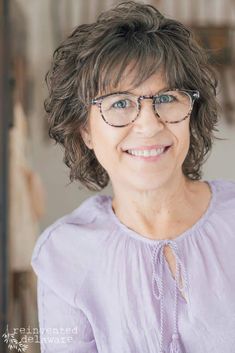 a woman with glasses smiling at the camera