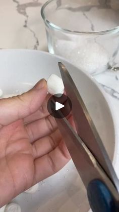 a person is cutting something with a pair of scissors in front of a bowl full of ice cubes