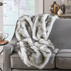 a gray couch with a white and grey fur throw