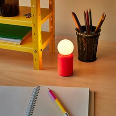 a notebook, pencils and lamp on a table