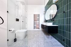 a bathroom with black and white tile walls, green tiles on the floor and a large mirror