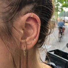 a close up of a person's ear wearing gold earrings