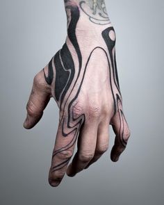 a man's hand with black and white tattoos on it