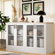 a white cabinet with glass doors and pictures on the wall