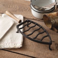 a wooden table topped with metal utensils next to a white bowl and napkin