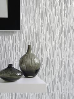 two black vases sitting on top of a white shelf