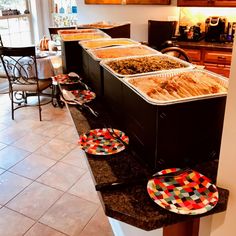 a counter with plates and bowls on it in a room filled with tables and chairs