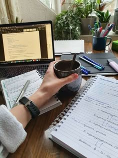 a person holding a coffee cup in front of a laptop