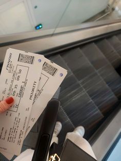 a person holding two tickets in their hand on an escalator