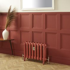 a room with red walls and a radiator in the corner, next to a table