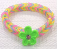 a bracelet with a green flower on it and multi colored braiding around the clasp