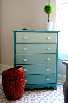 a blue dresser sitting next to a potted plant