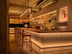 a bar with several stools and bottles on the wall